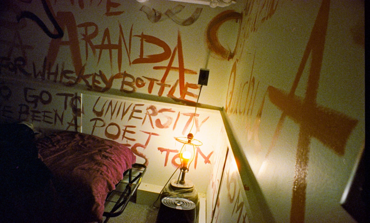 Wall covered in orange graffiti and writing. related to Unleashing Your Bedroom's Potential: Unique Bed Frames