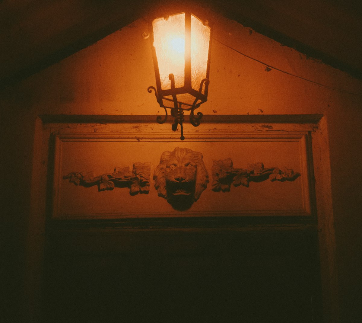 Warm lantern light illuminates a decorative lion head carving. related to Illuminating the First Impression: Entryway Light Fixture Ideas