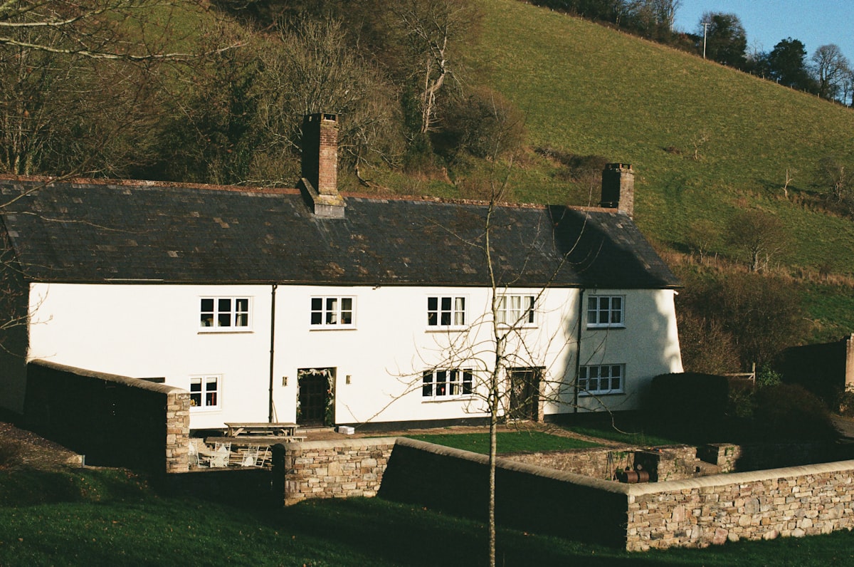 White farmhouse with stone walls and green hills. related to Discover the Charm of Bed and Breakfast Hill Country