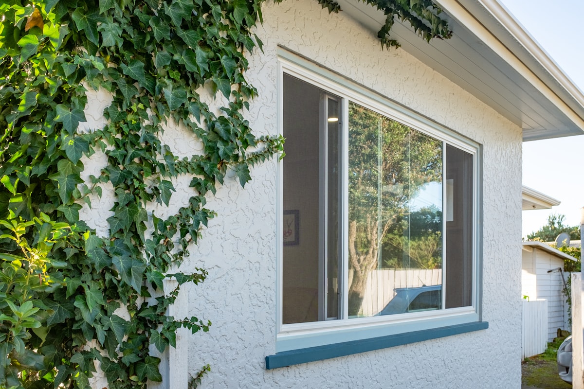 White stucco house with big window and vines related to Elevate Your Windows with Custom Valances and Cornices