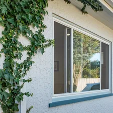 White stucco house with big window and vines related to Elevate Your Windows with Custom Valances and Cornices