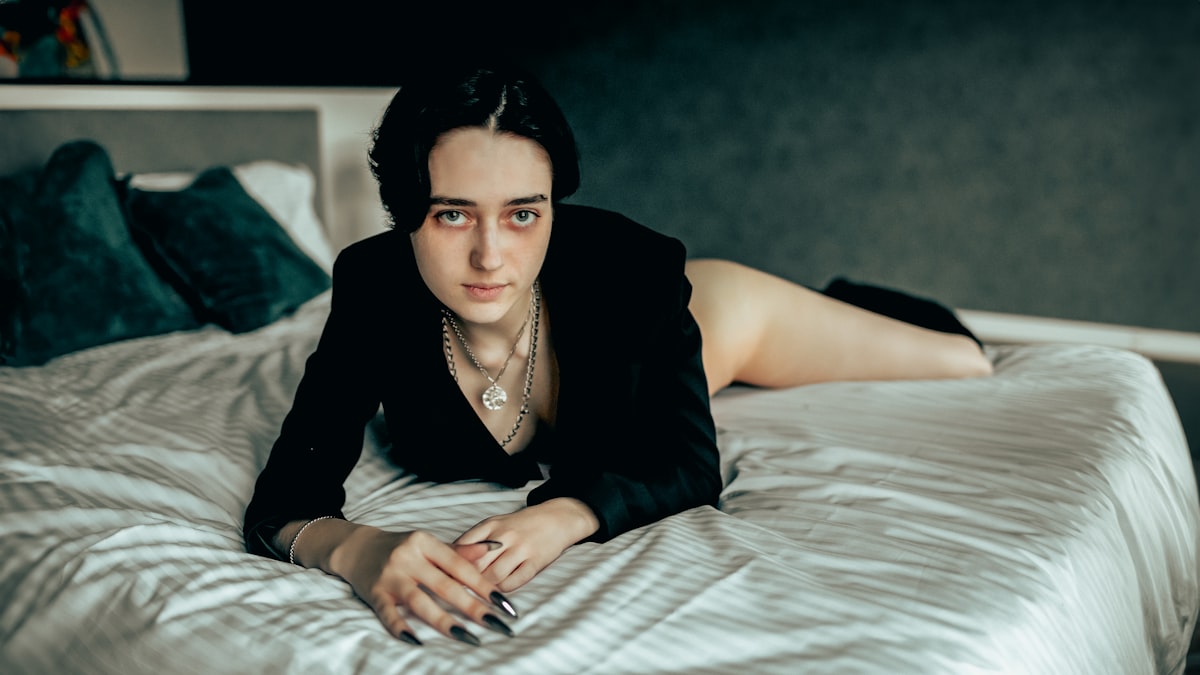 Woman in black blazer lying on a bed. related to Shania Twain: Unraveling the Lyrics of 'Whose Bed Have Your Boots Been Under?'