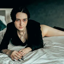 Woman in black blazer lying on a bed. related to Shania Twain: Unraveling the Lyrics of 'Whose Bed Have Your Boots Been Under?'