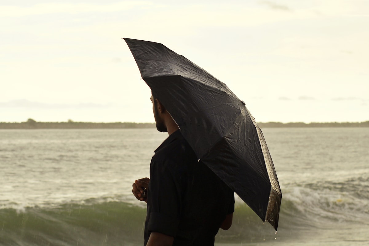 woman in black long sleeve shirt holding umbrella standing on seashore during daytime related to Bed Bath Beyond Umbrella: A Comprehensive Guide