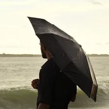 woman in black long sleeve shirt holding umbrella standing on seashore during daytime related to Bed Bath Beyond Umbrella: A Comprehensive Guide