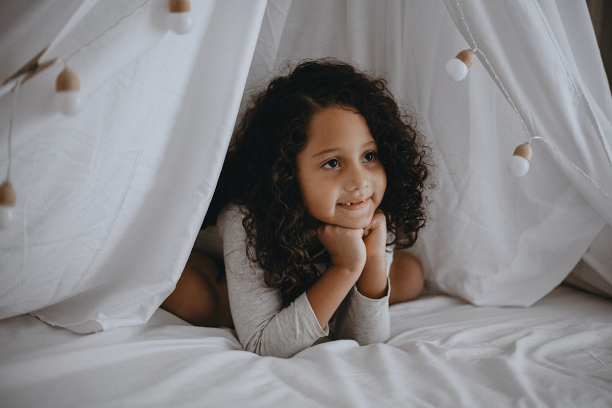 woman in gray shirt lying on bed related to Dreamland Delights: The Ultimate Guide to Toddler Bedding for Girls