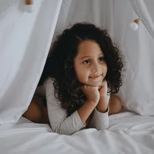 woman in gray shirt lying on bed related to Dreamland Delights: The Ultimate Guide to Toddler Bedding for Girls