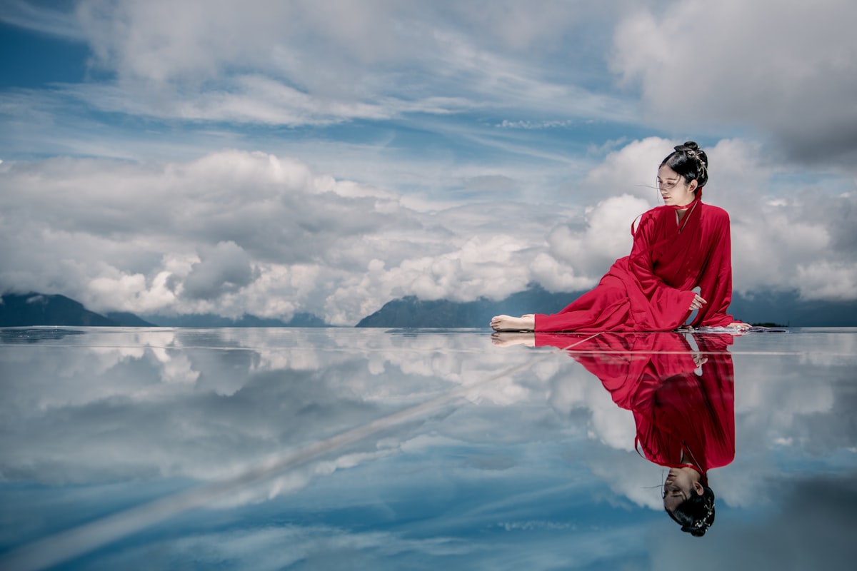 woman in red jacket and black pants standing on rock under white clouds and blue sky related to Elegance Redefined: Exploring the Beauty of Black Window Valances and Swags