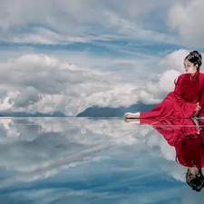 woman in red jacket and black pants standing on rock under white clouds and blue sky related to Elegance Redefined: Exploring the Beauty of Black Window Valances and Swags