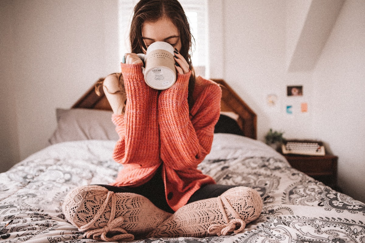 woman in red knit sweater holding white ceramic mug related to Power Up for Sleep: The Benefits of Drinking Milk Before Bed