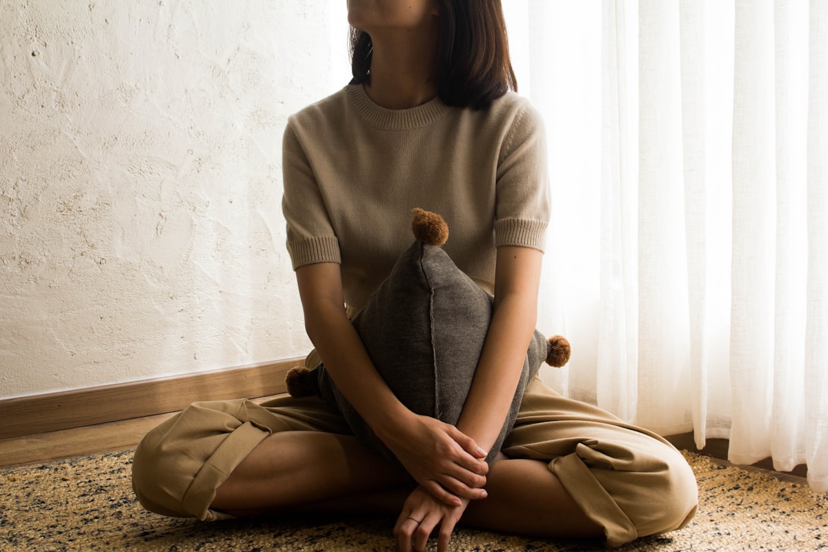 woman in white knit sweater sitting on brown wooden seat related to Best Pillows for Sitting Up in Bed: Ultimate Comfort Guide