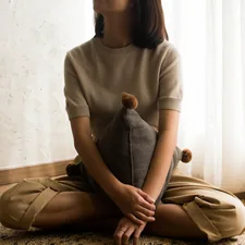 woman in white knit sweater sitting on brown wooden seat related to Best Pillows for Sitting Up in Bed: Ultimate Comfort Guide