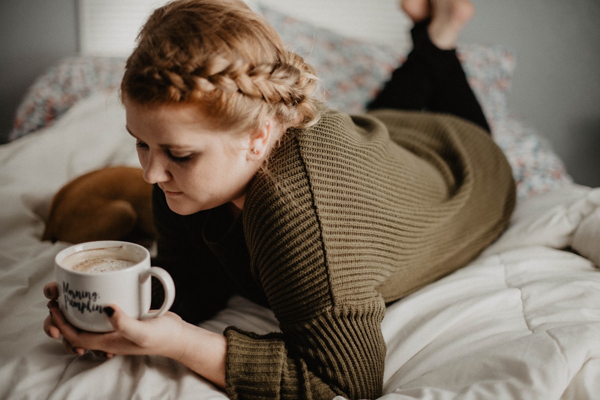 woman on bed holding white mug related to Power Up for Sleep: The Benefits of Drinking Milk Before Bed