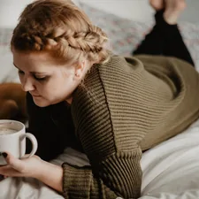 woman on bed holding white mug related to Power Up for Sleep: The Benefits of Drinking Milk Before Bed
