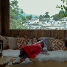 Woman relaxing on a couch with a scenic view. related to Your Mountain Escape Awaits at Comfort Bed and Breakfast