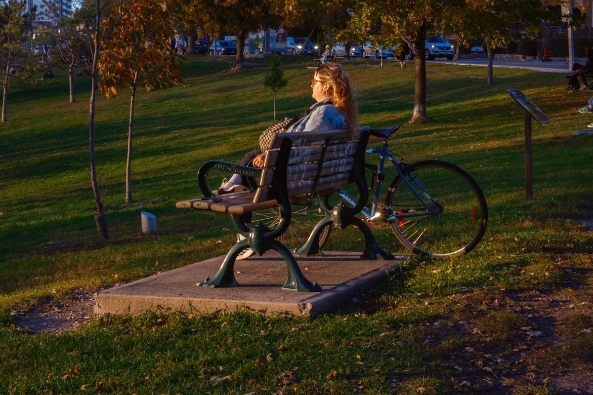 Woman sitting on park bench with bicycle related to The Ultimate Guide to Choosing the Perfect Bench for the End of Your Bed