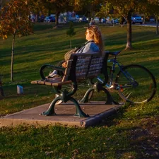 Woman sitting on park bench with bicycle related to The Ultimate Guide to Choosing the Perfect Bench for the End of Your Bed