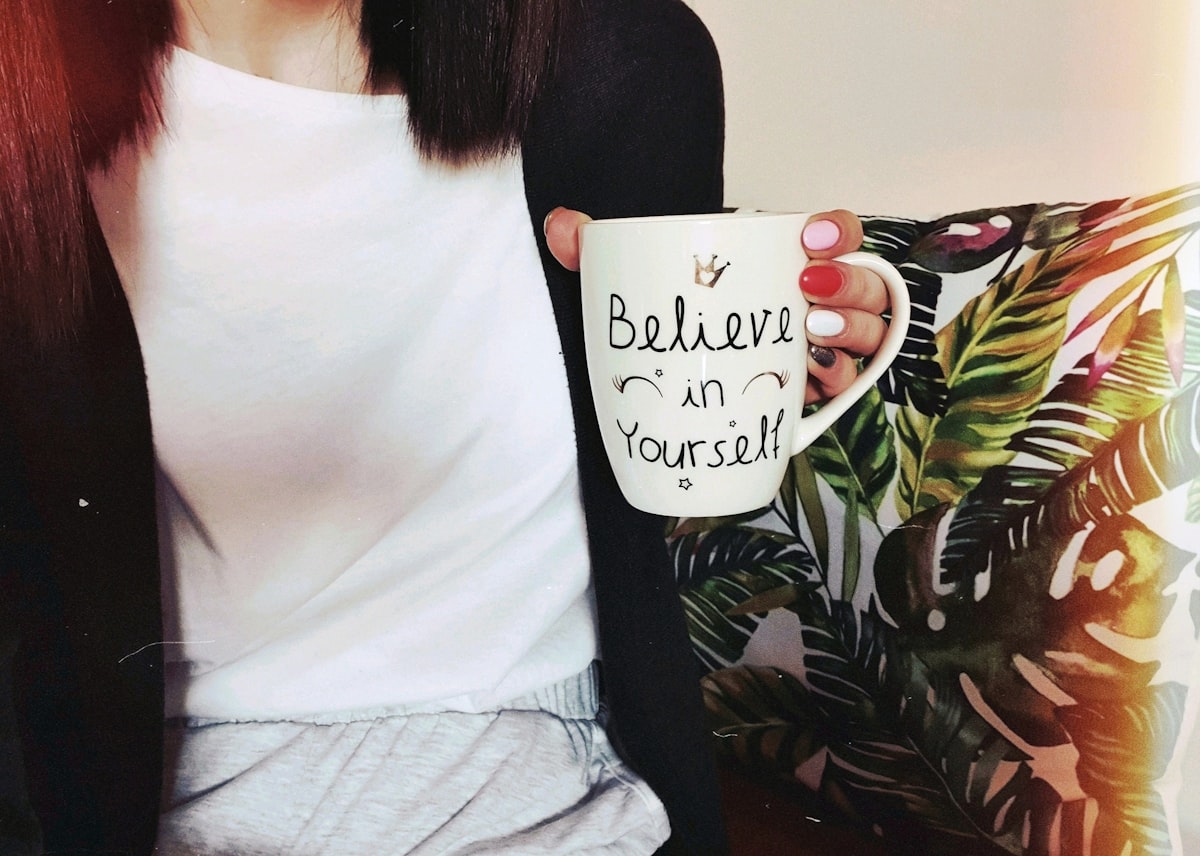 woman wearing black cardigan holding mug related to Unleash Your Inner Style: Three Original Takes on Scarf Valance Hooks