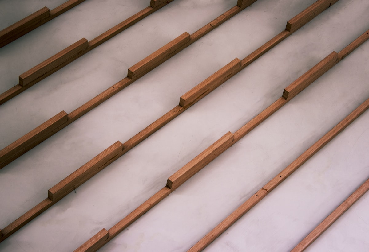 Wooden slats arranged diagonally on a light grey surface. related to The Ultimate Guide to Bed Slats Full