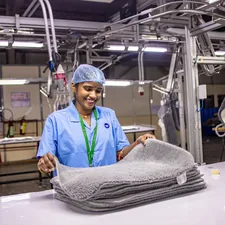 Worker inspecting folded textiles in a factory. related to Discover Empowering Opportunities at Bed Bath & Beyond