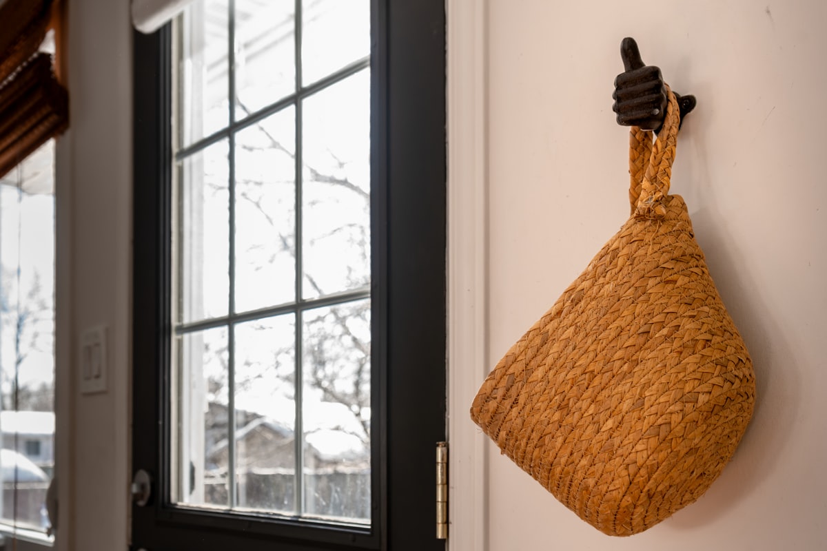 Woven basket hanging on a wall by a window. related to Revamp Your Entryway with a Stylish Mirror and Hooks