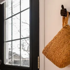 Woven basket hanging on a wall by a window. related to Revamp Your Entryway with a Stylish Mirror and Hooks
