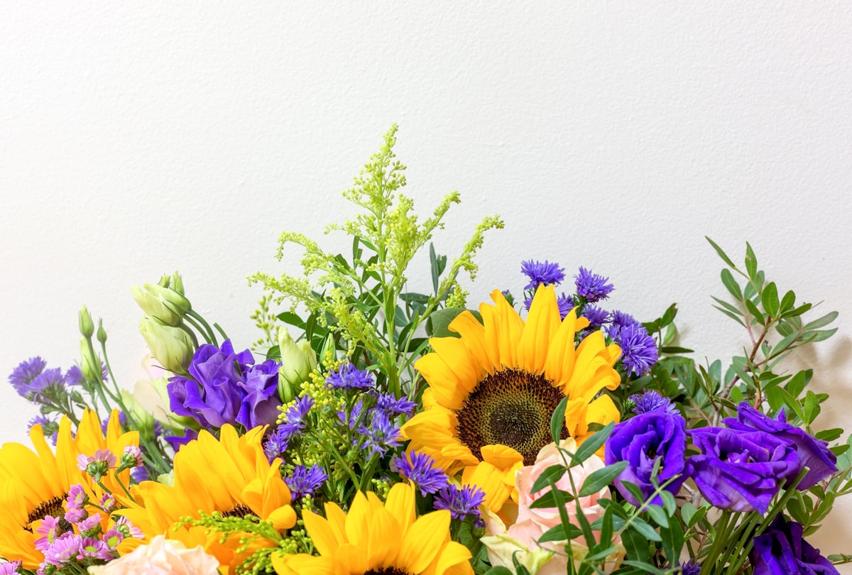 Yellow and purple flowers and greenery with negative space above. related to Brighten Your Space with Sunflower Valance Curtains