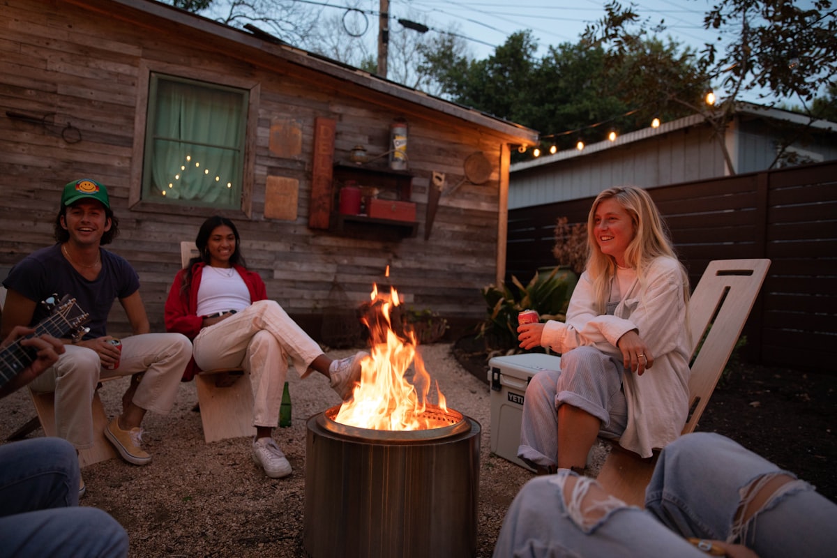 Young friends relaxing in the backyard around a firepit at night, on Trippy Chairs related to Cozy Up Your Backyard with Chimineas at Lowe's
